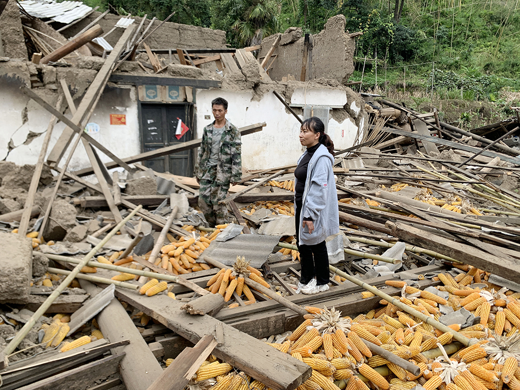 9月7日，在雅安市石棉县王岗坪彝族藏族乡幸福村二组，养蜜蜂为生的康贝兵（左）、陈云夫妇站在倒塌的房屋中。