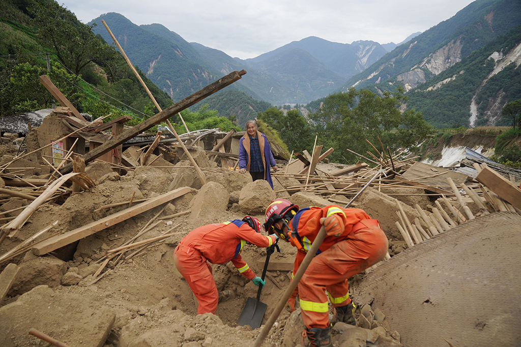 9月7日，四川眉山消防救援队队员在雅安市石棉县王岗坪彝族藏族乡幸福村二组，帮助村民在倒塌的房屋中找寻物品。