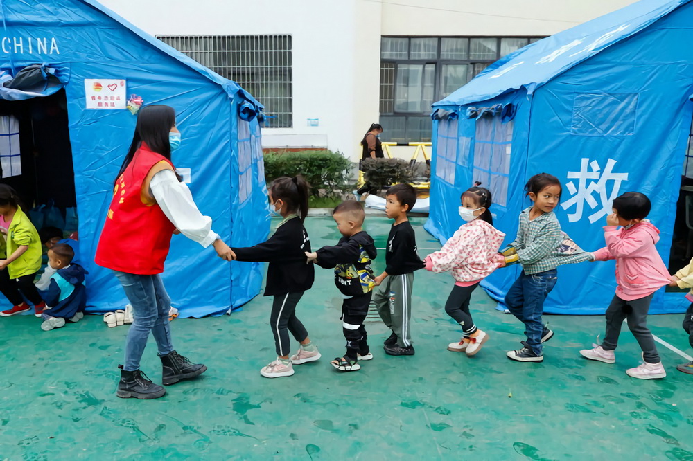 9月10日，在四川省甘孜州瀘定縣第二中學校地震災后臨時安置點，羅蓮（前左一）帶著孩子們排隊准備進入“帳篷課堂”。