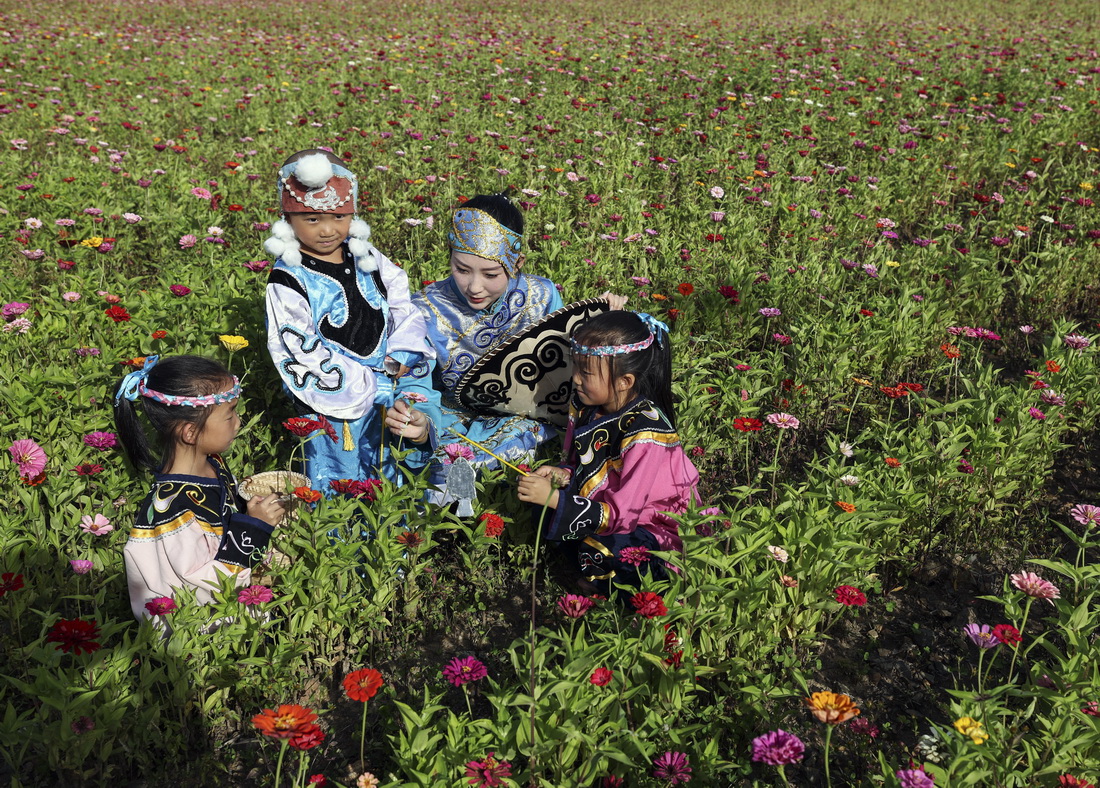 9月4日，在黑龙江抚远市乌苏镇抓吉赫哲族村，尚美含和学生们在花田里玩耍。新华社记者 兰红光 摄