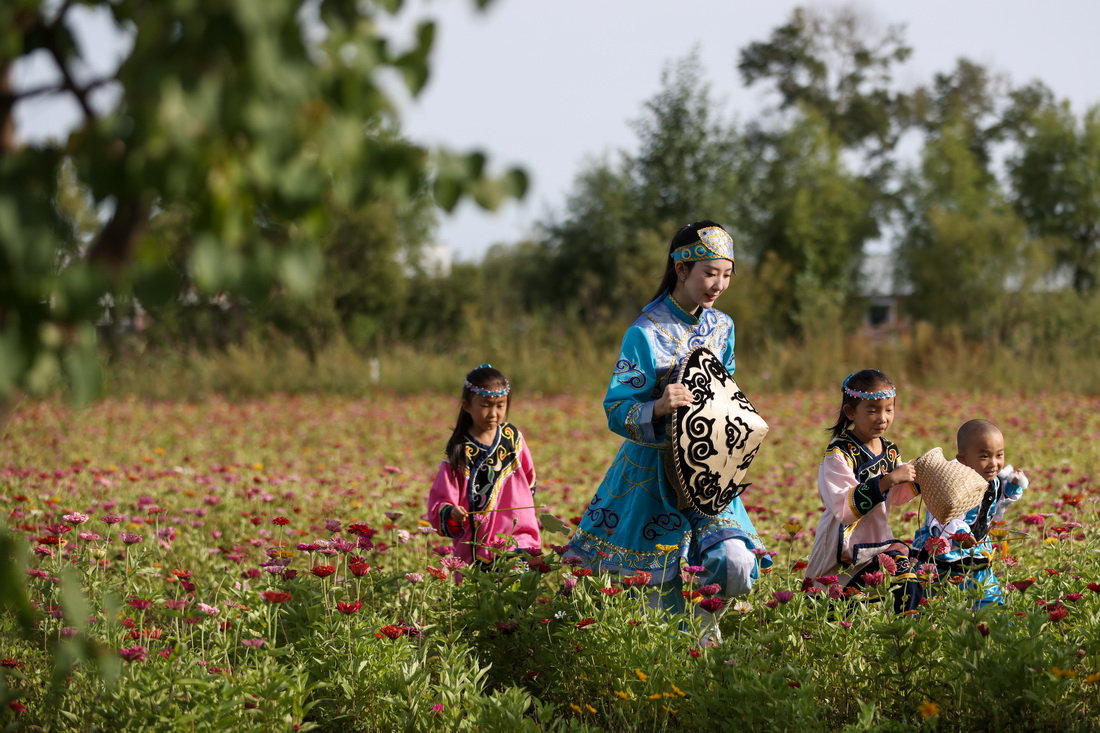 9月4日，在黑龙江抚远市乌苏镇抓吉赫哲族村，尚美含（左二）领着学生在花田里玩耍。新华社记者 张涛 摄