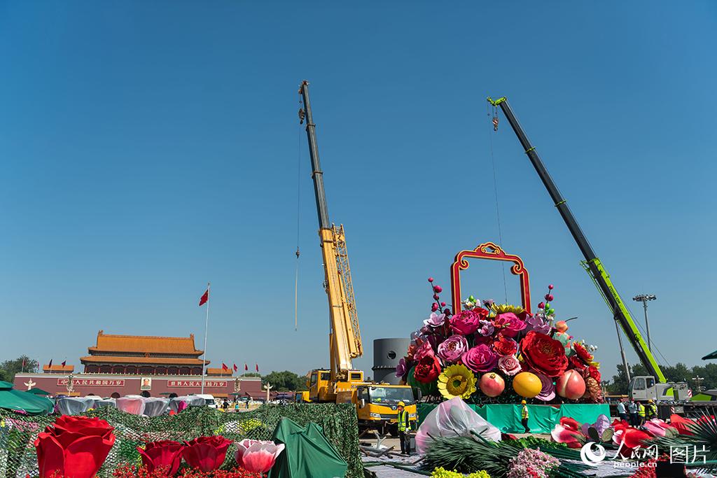 9月21日，在北京天安门广场，工作人员正在搭建国庆大花篮，各种巨大的花朵、水果模型在空中吊装。人民网记者 翁奇羽摄