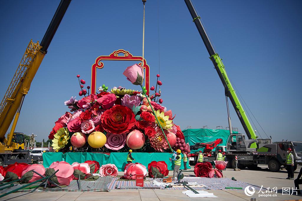 9月21日，在北京天安门广场，工作人员正在搭建国庆大花篮，各种巨大的花朵、水果模型在空中吊装。人民网记者 于凯摄