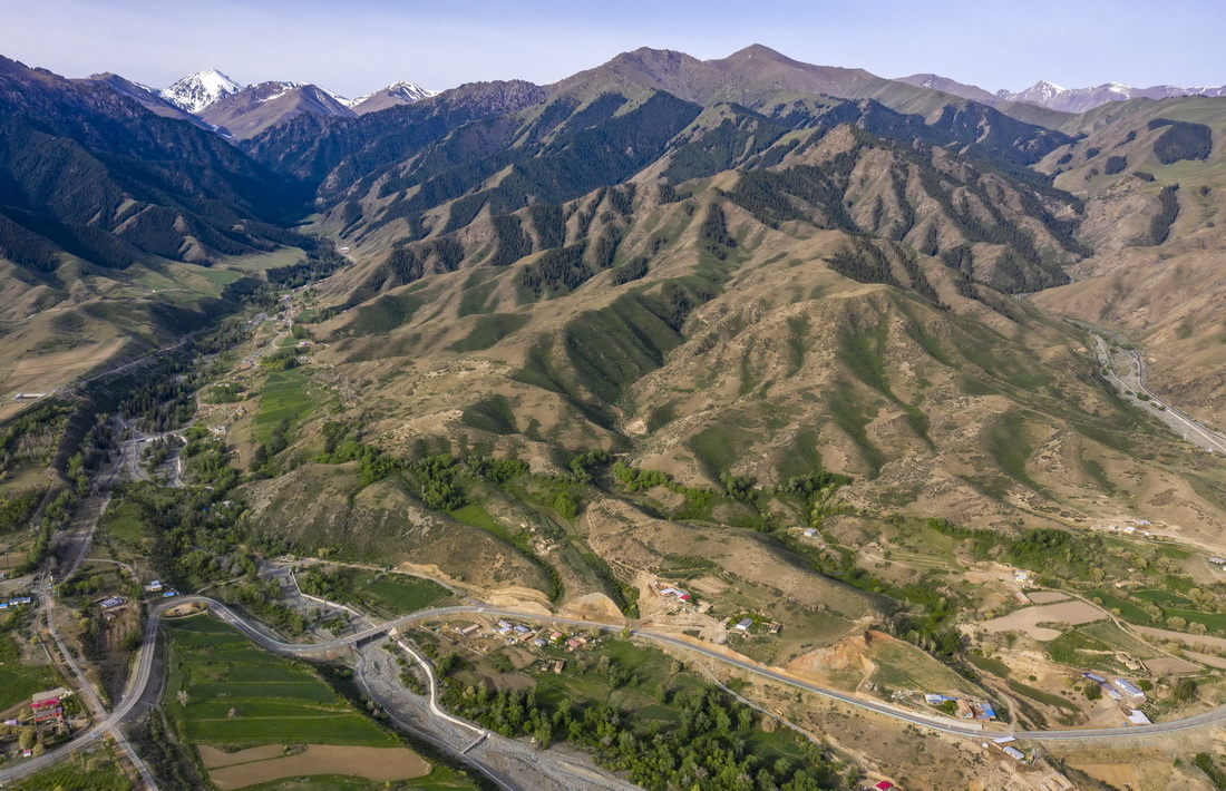 新疆吉木薩爾縣新地鄉的一處伴山鄉間公路（2022年5月22日攝，無人機照片）。路旁的小分子村發展鄉村旅游，成為遠近聞名的“畫家村”。新華社記者 胡虎虎 攝