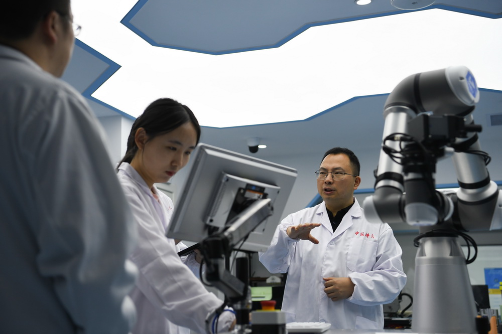 10月21日，中國科學技術大學化學物理系江俊教授（右）在實驗室與團隊成員交流。