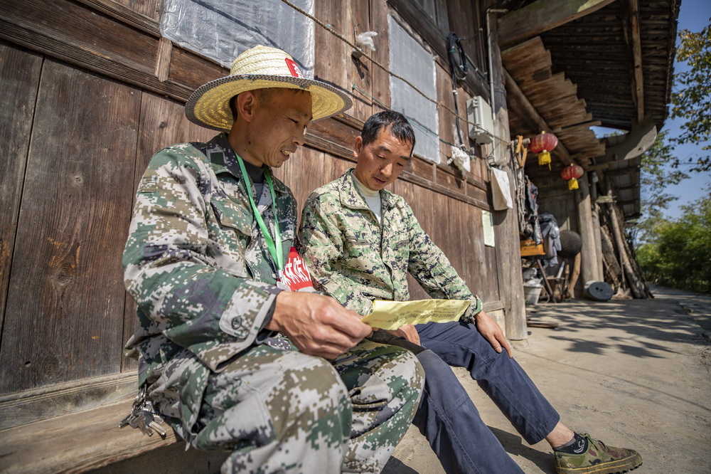 10月21日，在重慶金佛山國家級自然保護區，護林員張廷剛（左）在巡山路途中向村民宣傳森林防火知識。