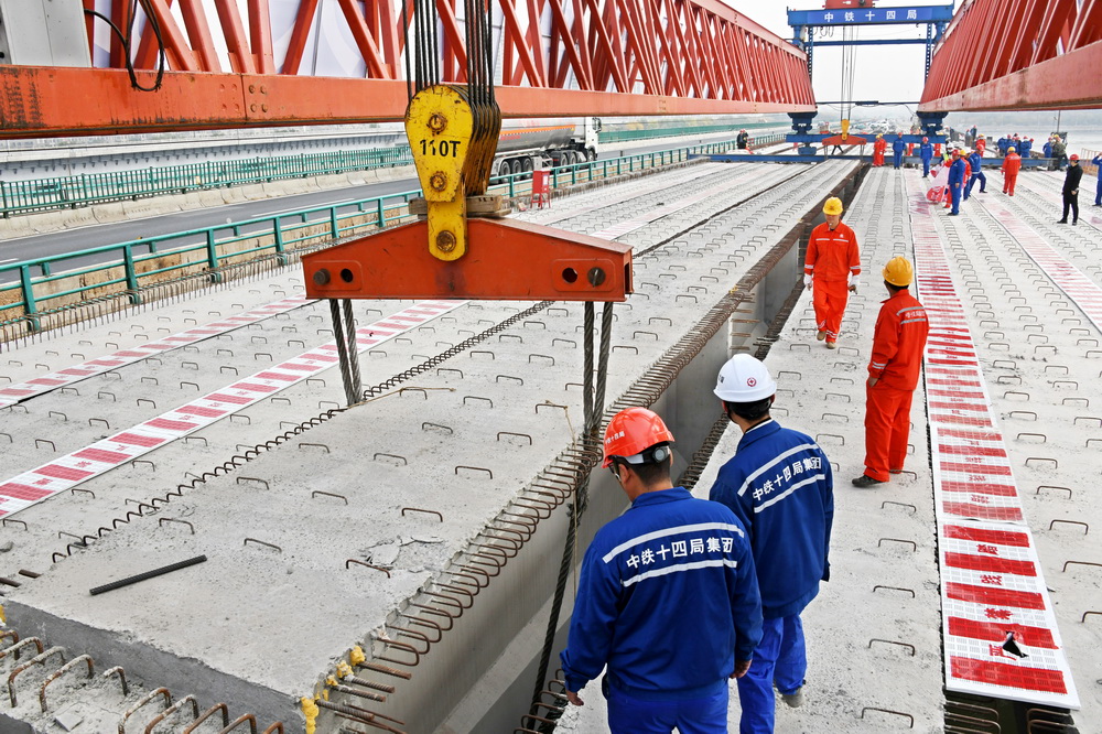 10月30日，青蘭高速公路雙埠至河套段女姑口特大橋施工現場，中鐵十四局建設者在吊放最后一片50米T梁。