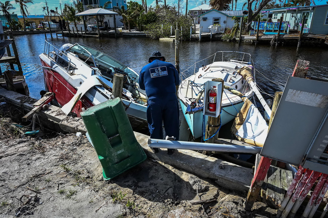 11月7日，在美国佛罗里达州西南部李县，美国海岸警卫队工作人员查看被飓风“伊恩”损坏的船只。