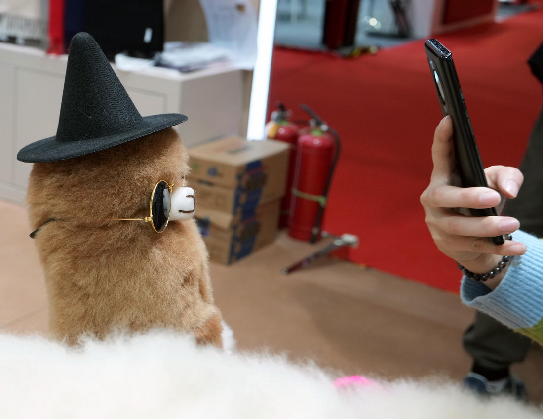 11月8日，在第五屆進博會上，參觀者拍攝“溫暖駝”展台的羊駝玩偶。新華社記者 劉穎 攝