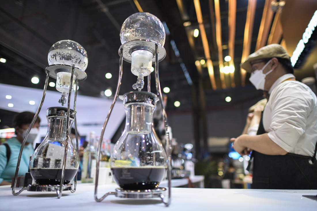 11月9日，在第五屆進博會食品及農產品展區，一處展台的工作人員在冰滴咖啡壺旁與參觀者交流。新華社記者 戴天放 攝