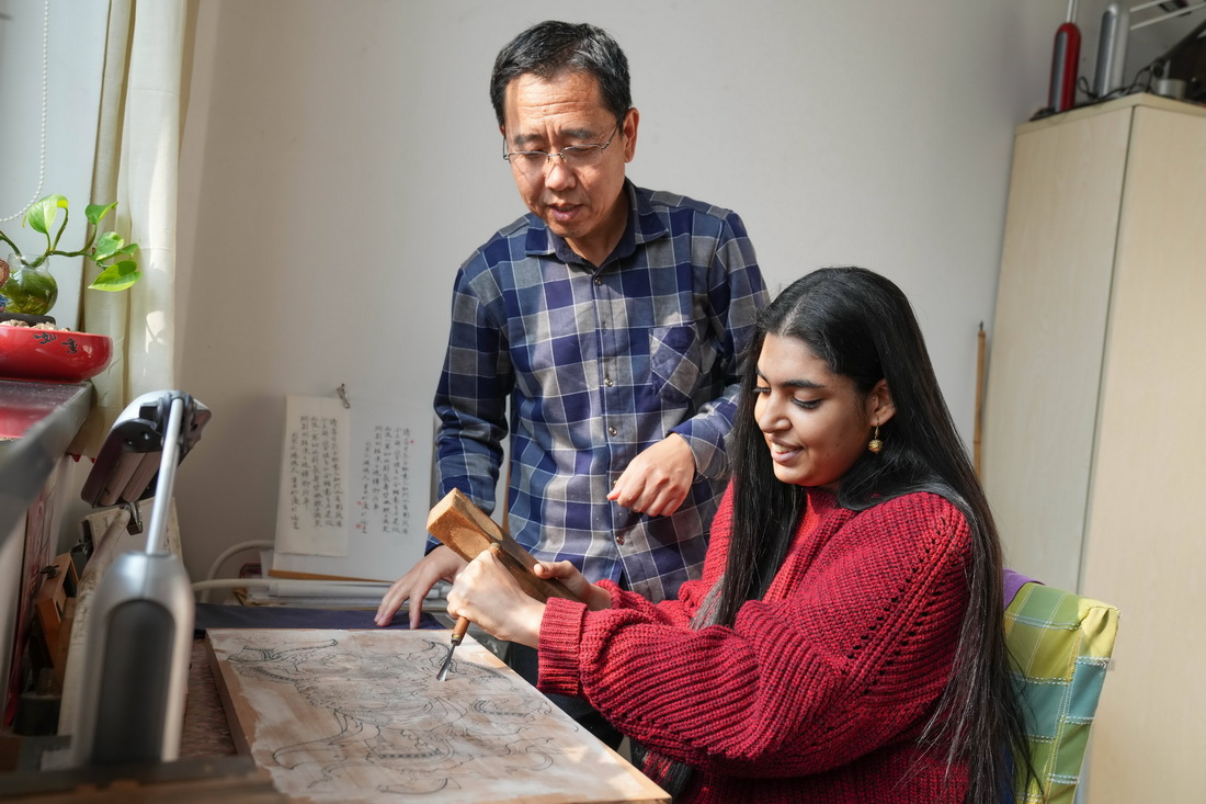 在天津杨柳青木版年画博物馆，辛格在天津市级非遗艺人刘杰的指导下体验雕刻年画的印版（11月17日摄）。 新华社记者 孙凡越 摄