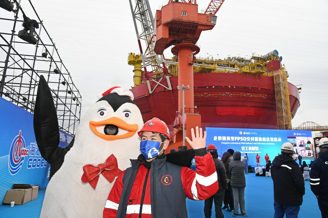 11月29日，一名工人在企鵝圓筒型浮式生產儲卸油裝置（FPSO）交付儀式上與吉祥物合影。