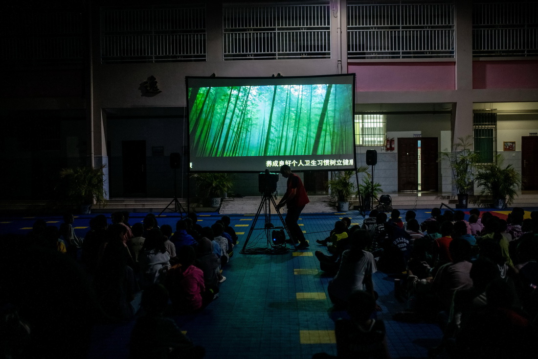 在怒江州泸水市，杨明金给特殊教育学校的孩子放电影（2022年10月22日摄）。