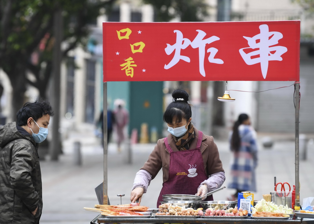 12月2日，重慶市南岸區居民（左一）在一炸串攤選購食品。