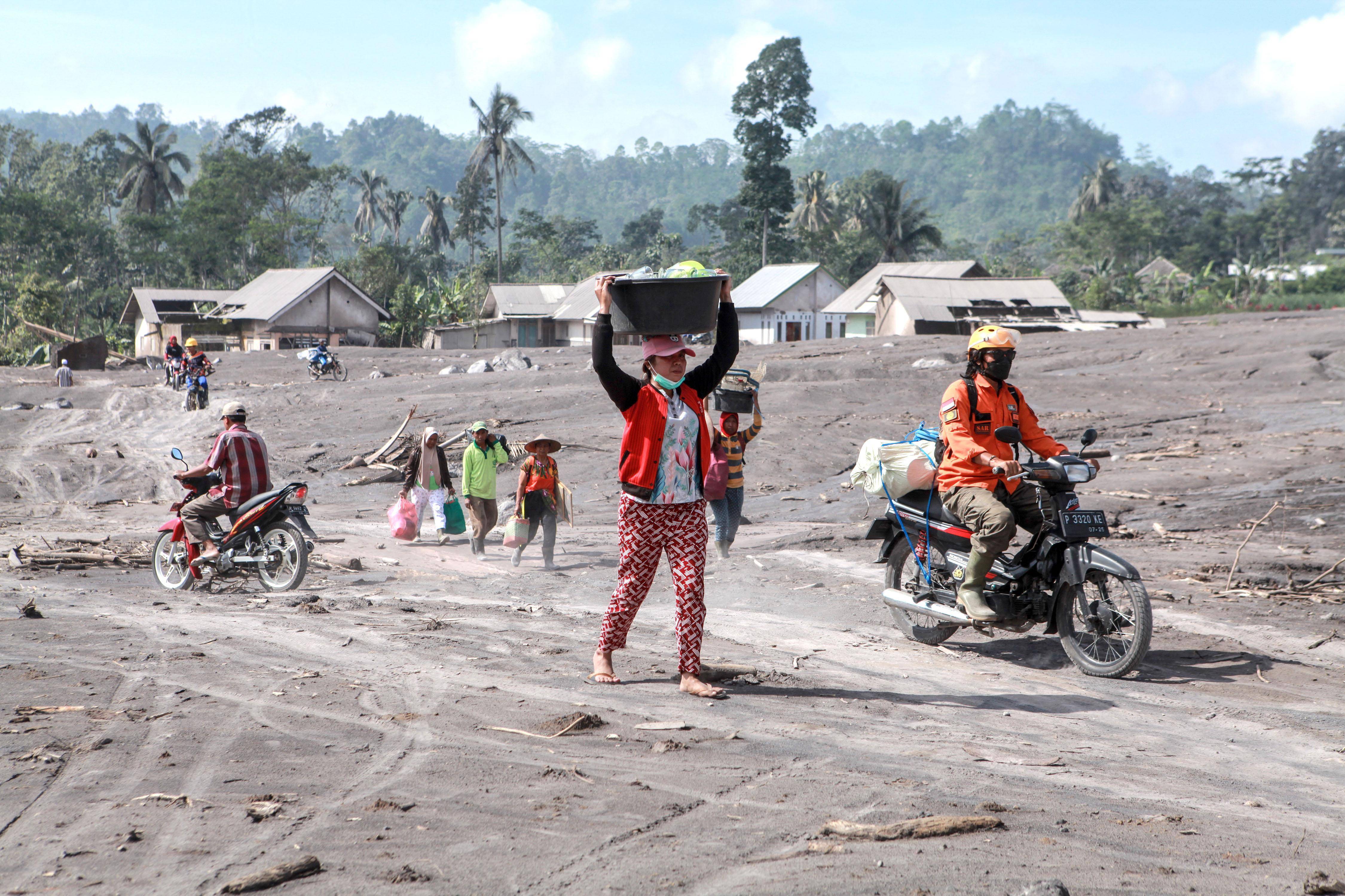 12月6日，在印度尼西亞東爪哇省盧馬姜縣鬆伯武盧村，人們攜帶物品撤離受火山噴發影響的區域。