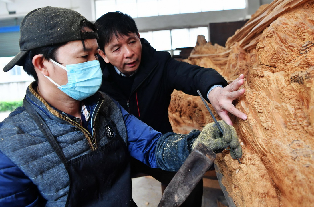 12月14日，国家级非遗项目莆田木雕省级代表性传承人郑春辉（右）在向员工传授雕刻技艺。