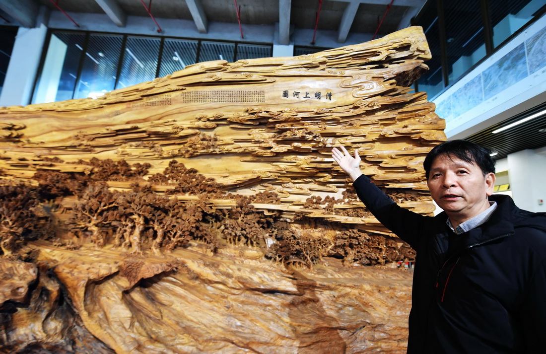 12月14日，国家级非遗项目莆田木雕省级代表性传承人郑春辉在介绍他的大型木雕作品《清明上河图》。该件作品历时近4年，在一棵长13米、最大直径达3.5米的千年古樟木上雕刻而成。 