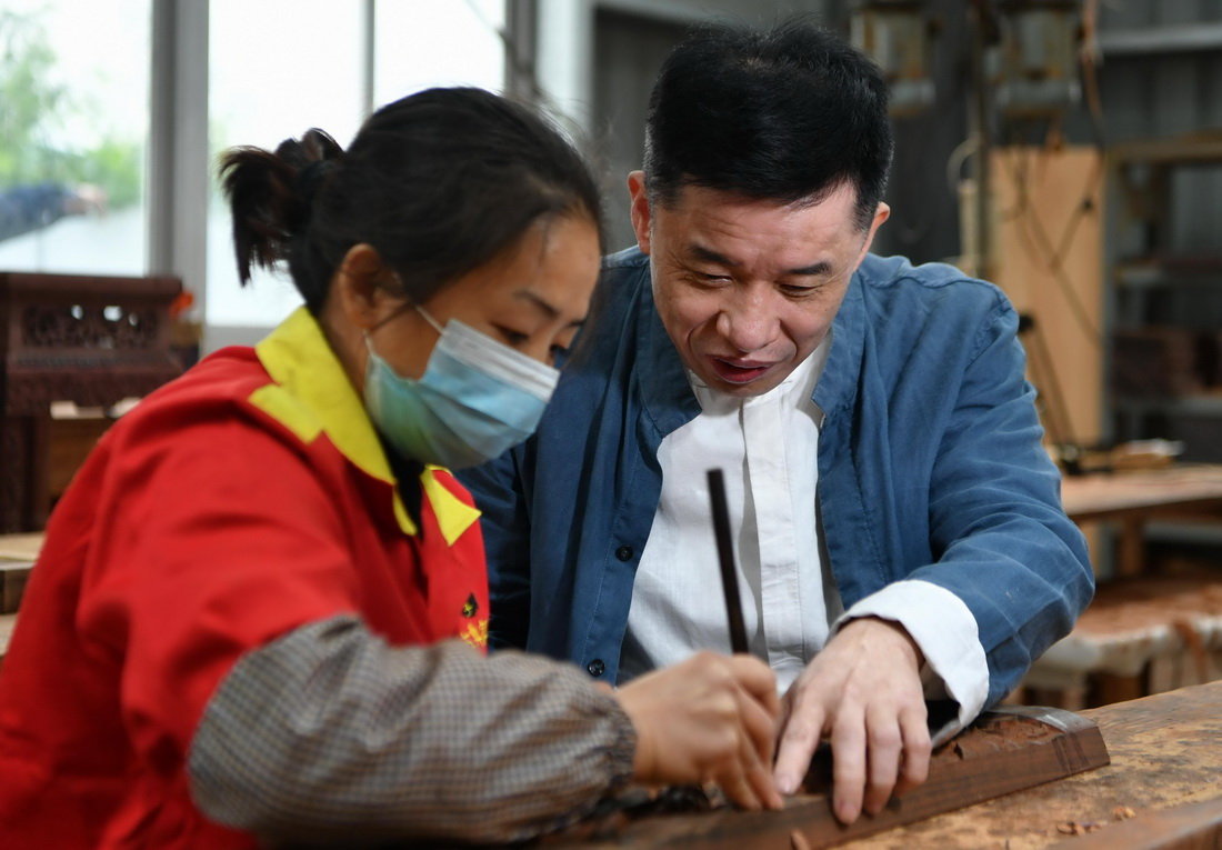 12月14日，古典家具技艺传承人陈玉树（右）指导员工进行雕刻。 