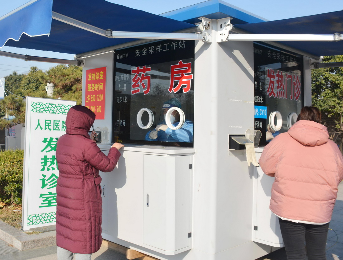 12月19日，在山東省棗庄市台兒庄區興中廣場，市民在一處發熱診室就診、取藥。新華社發（賈禮章 攝）