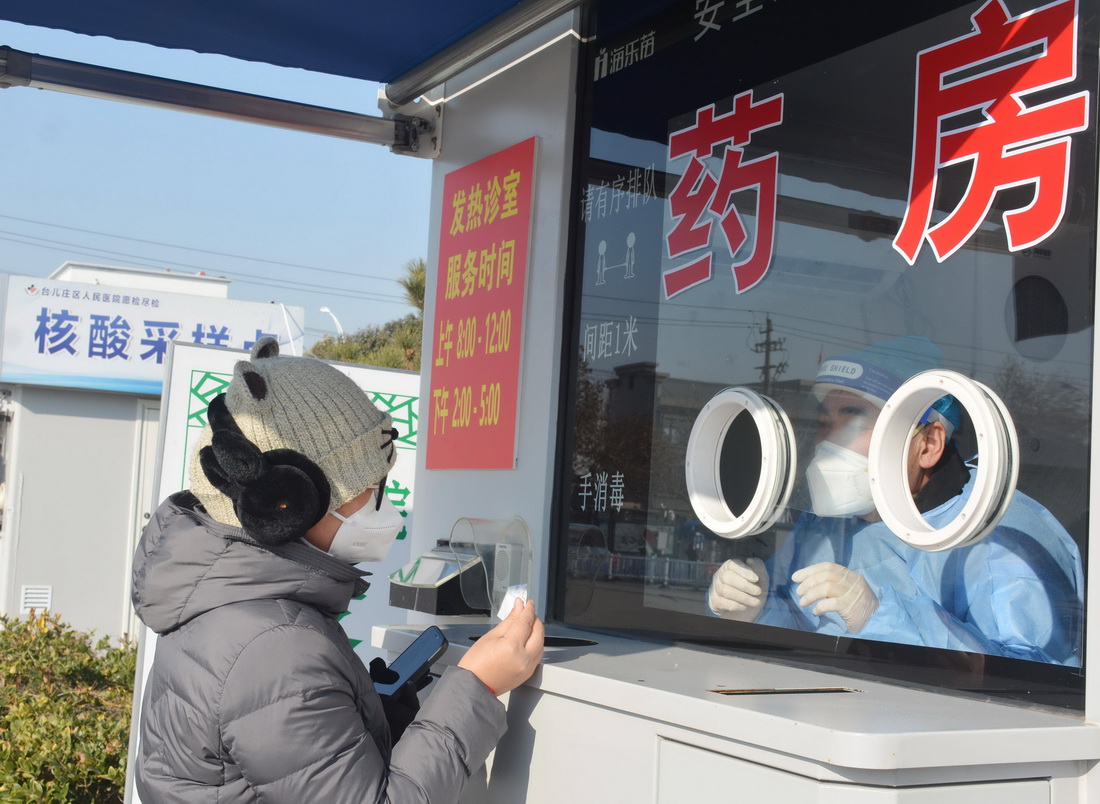12月19日，在山東省棗庄市台兒庄區興中廣場，市民在一處發熱診室取藥。新華社發（賈禮章 攝）