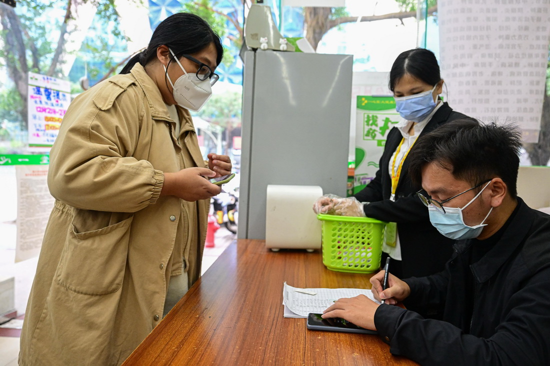 12月21日，在海口市一家药店，工作人员对前来领取药品的人员进行登记。