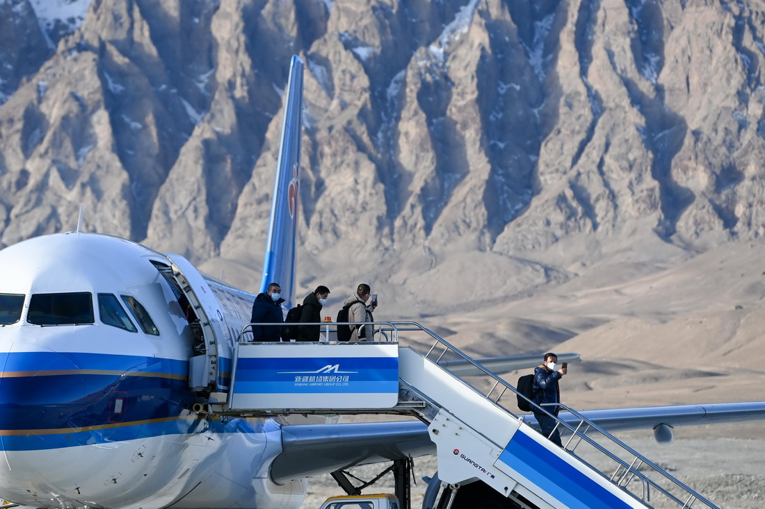 12月23日，在塔什库尔干红其拉甫机场，乘坐首航航班的旅客走下飞机。新华社记者 丁磊 摄