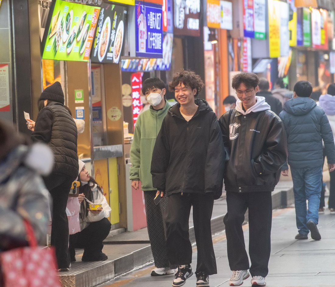12月23日，年輕人在位於重慶解放碑商圈的八一路好吃街上逛街。