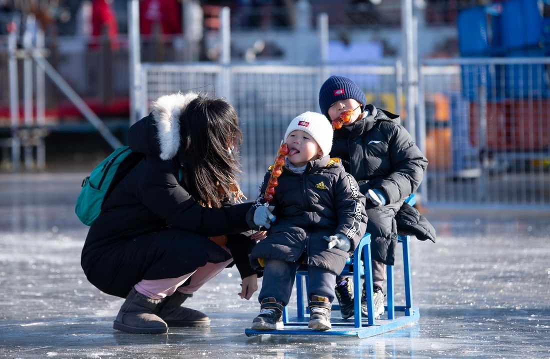 12月27日，在北京什剎海冰場，兩名小朋友坐在冰車上吃糖葫蘆。