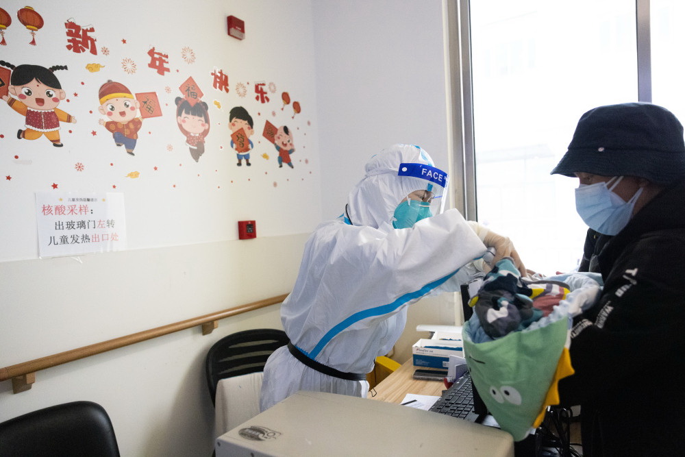 12月27日，在上海交通大學醫學院附屬新華醫院兒科發熱門診預檢台前，護士給患兒測體溫。