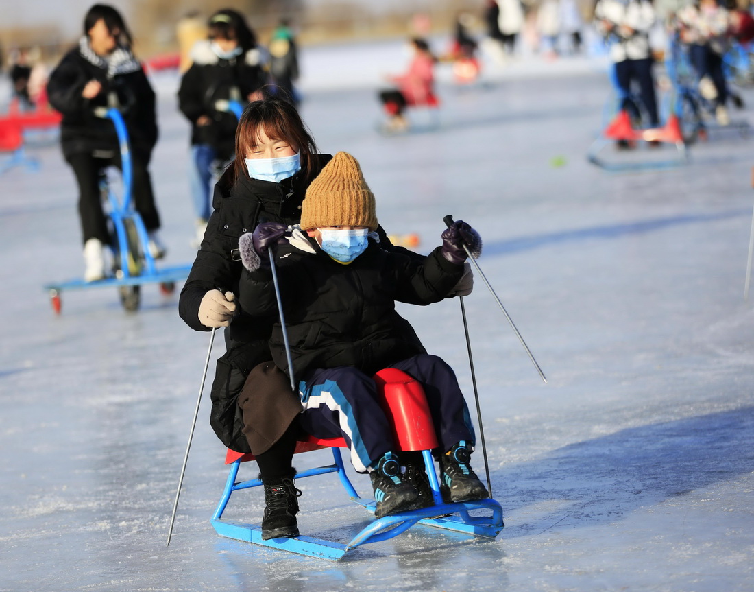 1月1日，市民在甘肃张掖国家湿地公园滑冰场坐滑冰车。 新华社发（陈礼摄）