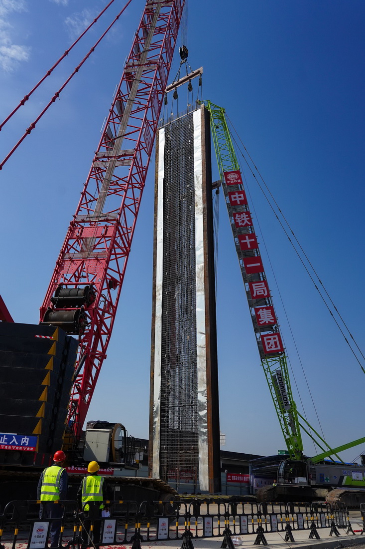1月7日，在深江鐵路深莞隧道西段出口明挖隧道施工現場，兩台吊機配合著將首幅地連牆鋼筋籠抬吊至垂直位置。
