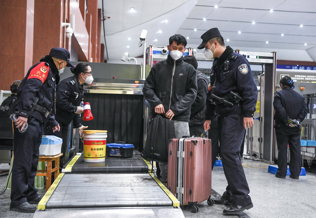 1月8日，铁路警察王云（前左一）和谢源（前右一）在贵阳东站督导乘客进站安检情况。