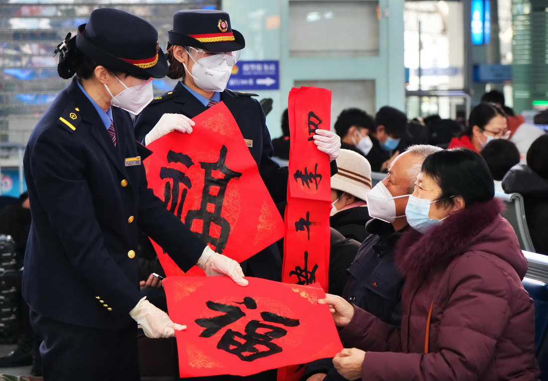 1月14日，天津站工作人员在候车大厅为旅客送上春联、福字。