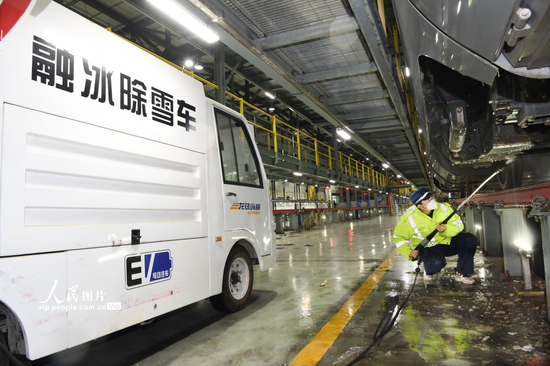 1月14日晚，郑州动车段动车组机械师在检修库对动车车底进行融冰除雪作业。