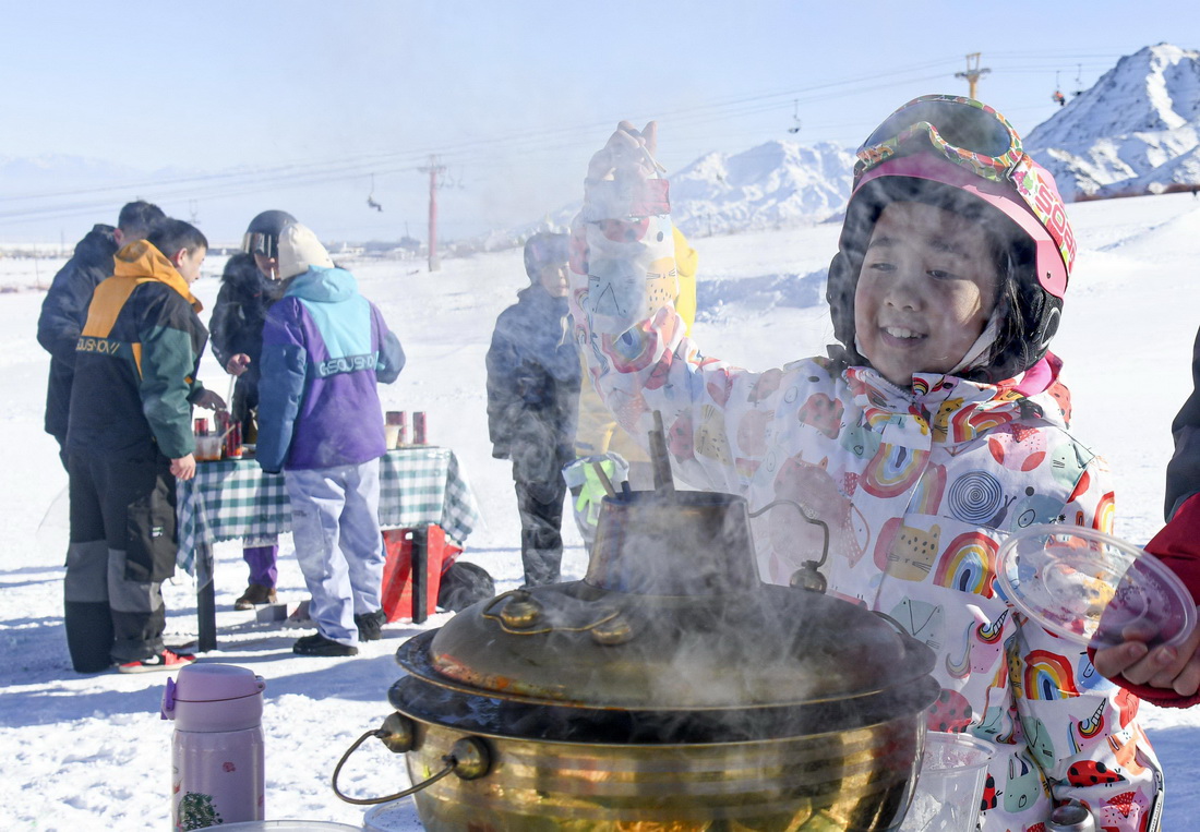 在新疆白雲國際滑雪場上，一名小朋友在雪場舉辦的冰雪火鍋節上等待品嘗美食（1月13日攝）。