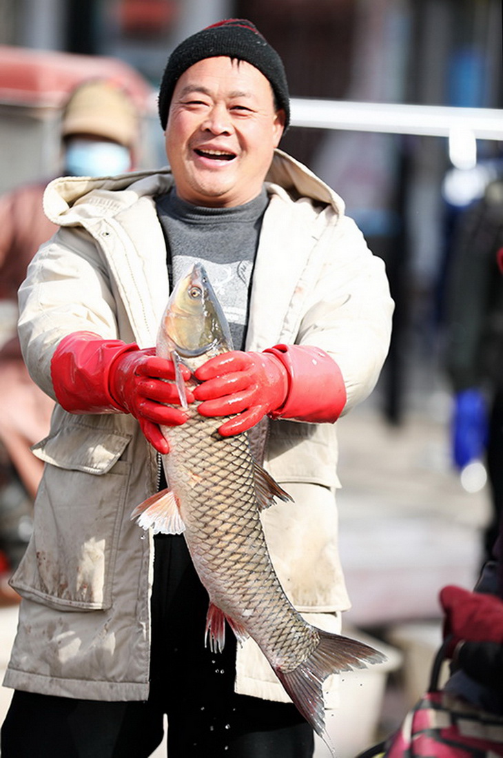 1月15日，在山東省臨沂市郯城縣郯城街道十裡年集上，一名攤主在售賣鮮魚。新華社發（張春雷 攝）