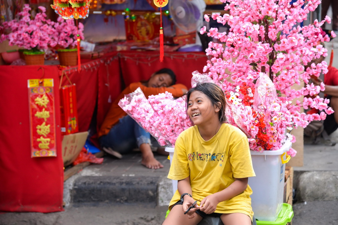 1月16日，在印度尼西亞雅加達中國城，一名小女孩坐在售賣年貨的街邊商鋪前。
