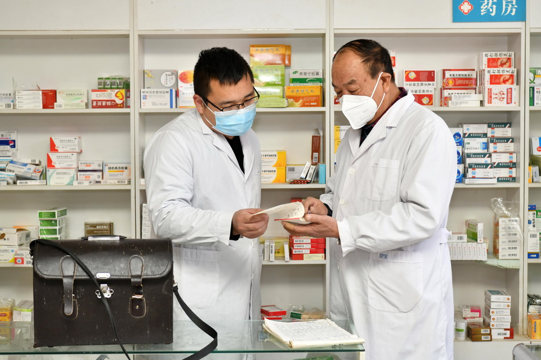 1月20日，南红星（右）和儿子南洋阳在村卫生室内交流当天诊治分工事宜。