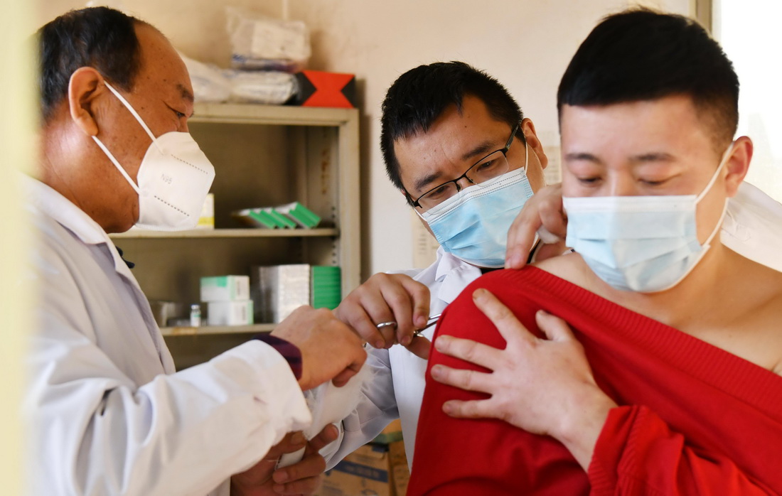 1月20日，南红星（左一）和儿子南洋阳（中）在村卫生室为患者换药。