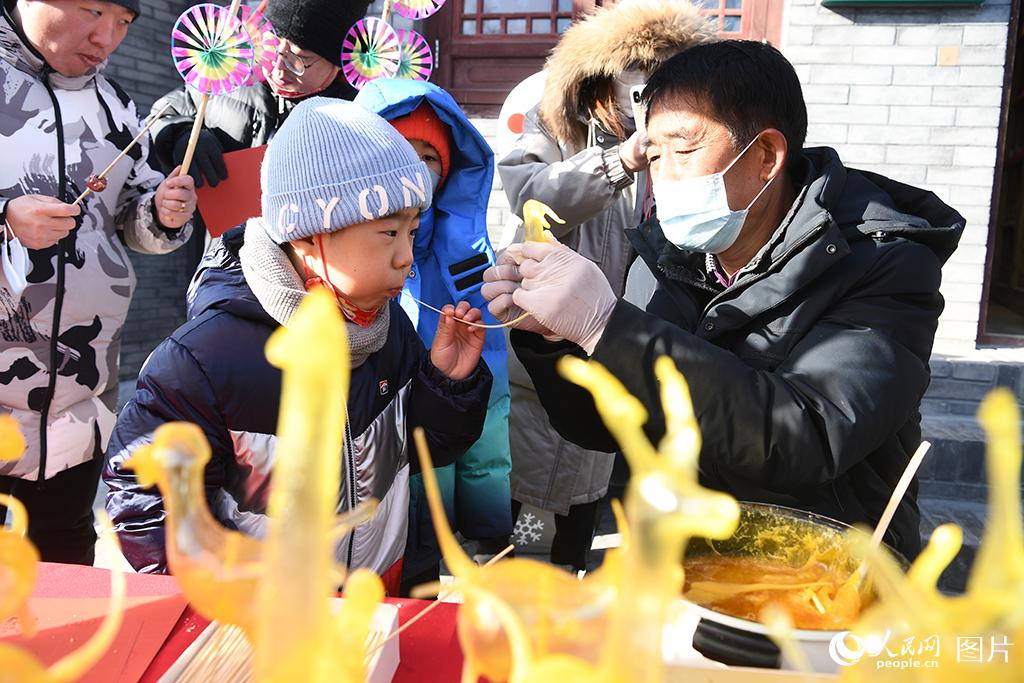 1月25日，北京石景山區模式口文化街，小朋友正在藝人的指導下吹糖人。人民網記者 於凱攝