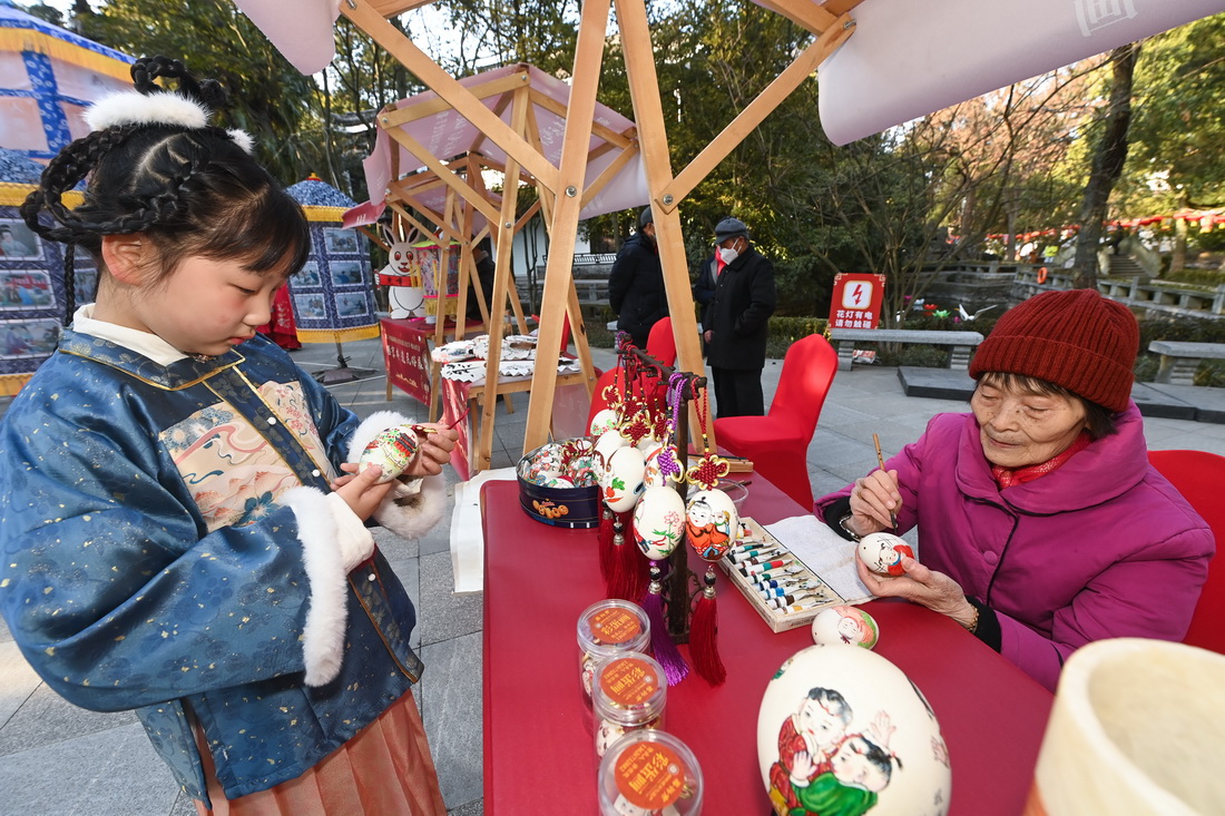 1月29日，在嘉興市秀洲區新塍古鎮小蓬萊公園內，傳統藝人（右）在“鰲山燈會”現場展示蛋畫技藝。
