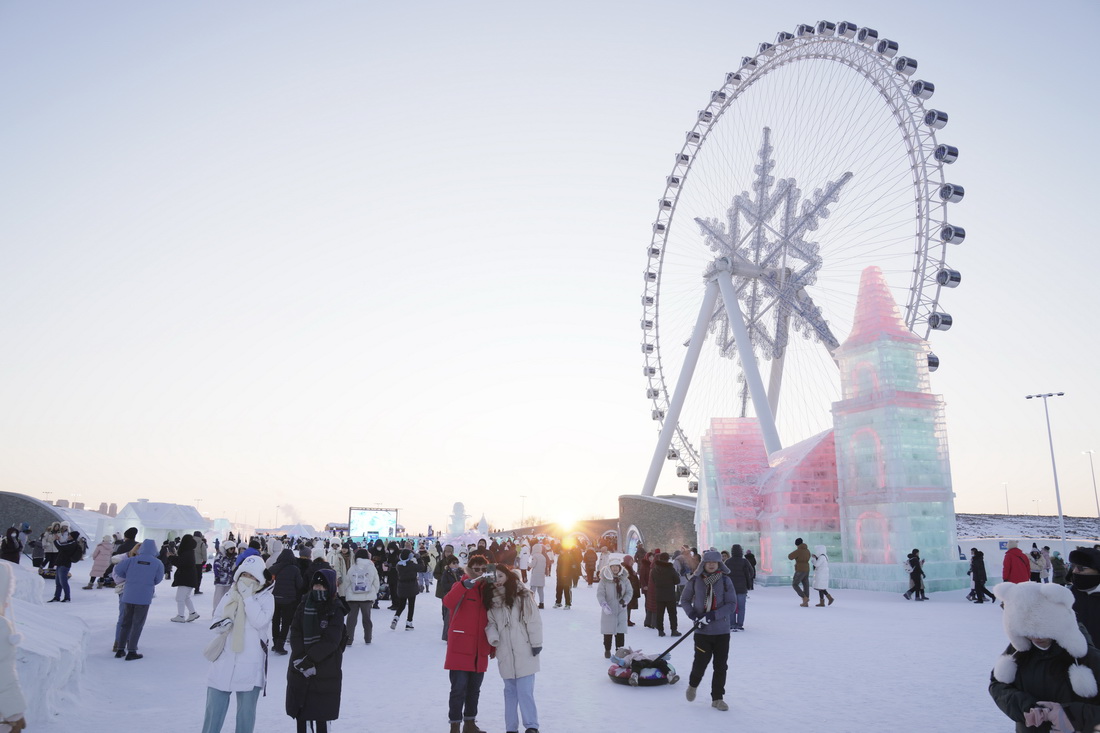 2月2日，游客在哈爾濱冰雪大世界園區內的“雪花摩天輪”附近游玩、拍照。