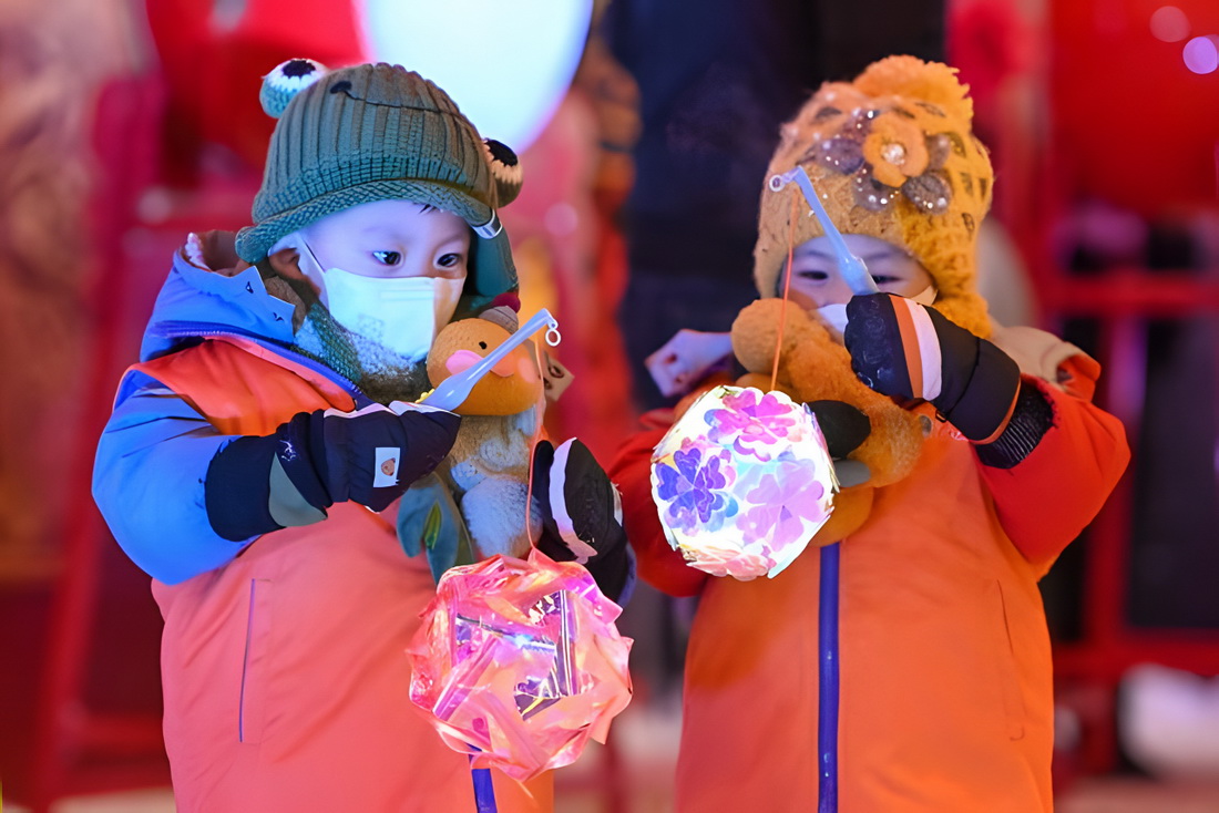 乌鲁木齐七一东街广场，小朋友提着花灯游玩（2023年1月22日摄）。新华社记者 丁磊 摄