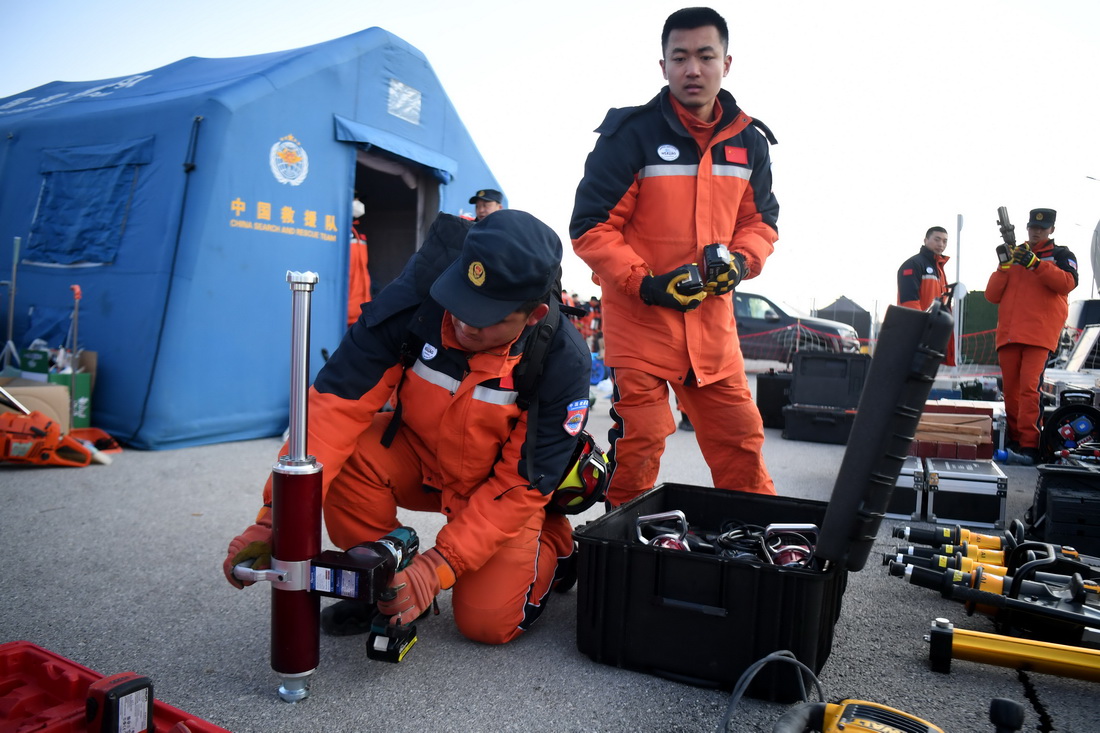 2月11日，在位于土耳其哈塔伊省哈塔伊体育馆外的中国救援队营地，救援队队员检查设备。