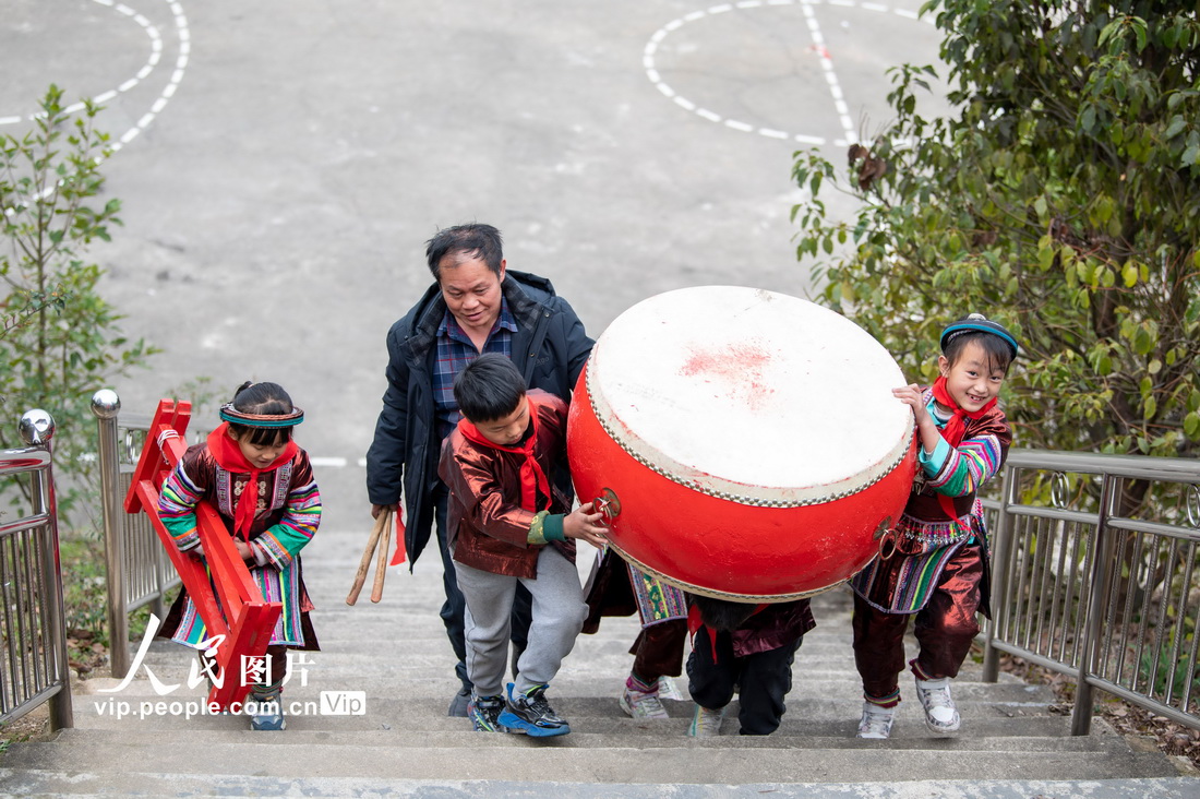 2023年2月16日，贵州省从江县西山镇中寨教学点教师孟荣达与学生一起搬运大鼓。