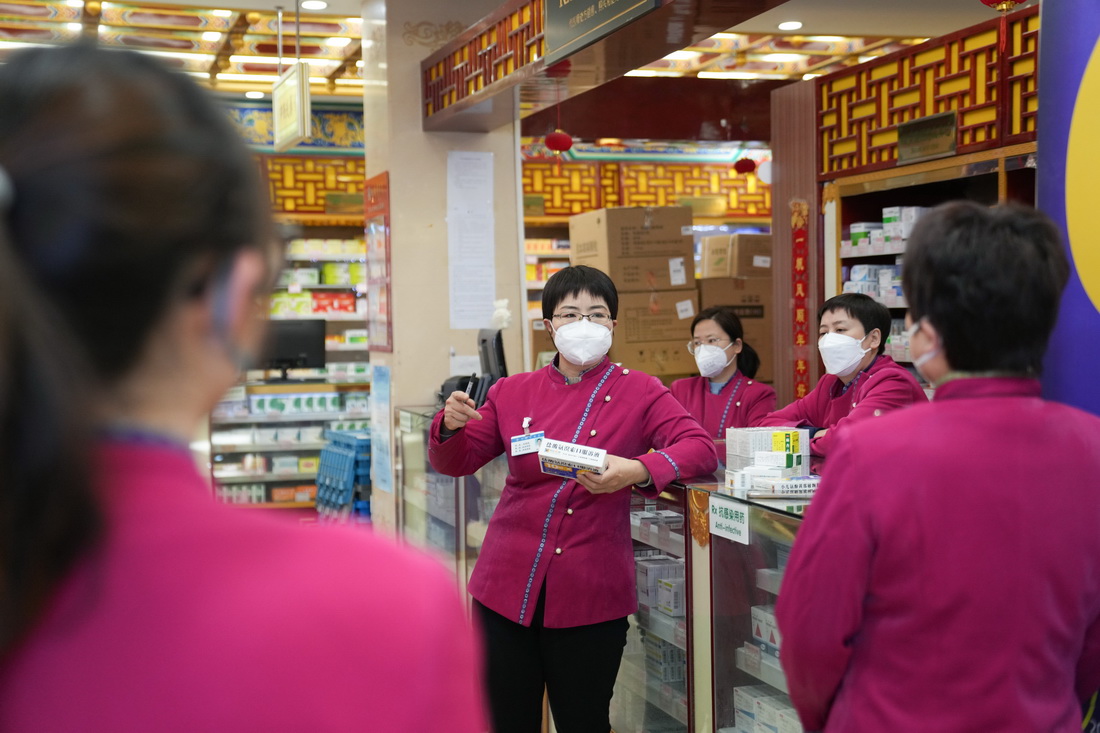 在白塔寺藥店，張海鷗（左二）和同事們一起分享藥物知識，進行班前學習（2月22日攝）。