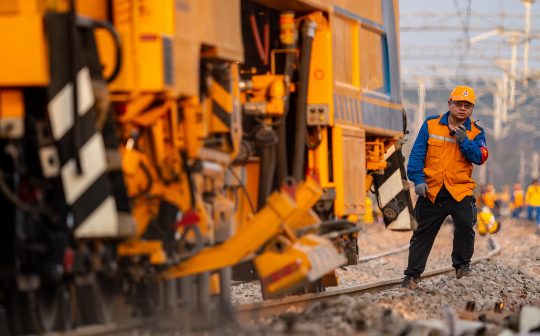 作业人员指挥养路机械对铁路进行线路捣固作业（3月8日摄）。