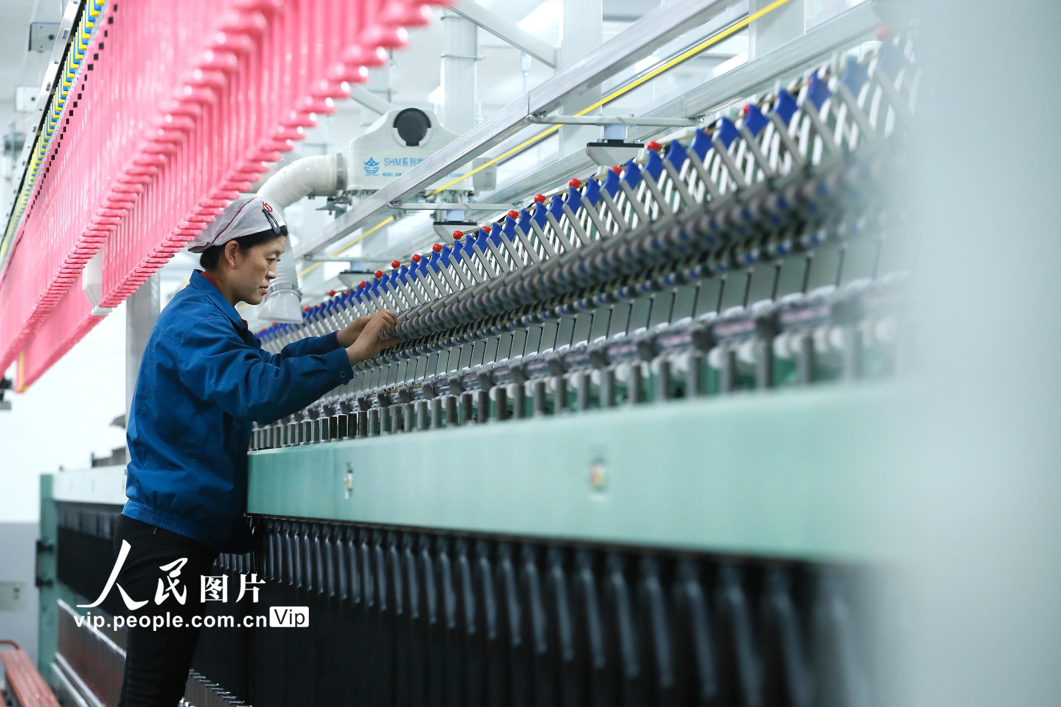 2023年3月26日，技术工人在山东省青岛市即墨区即发龙山工业园的一处数字化纺纱智能工厂项目调试安装生产设备。