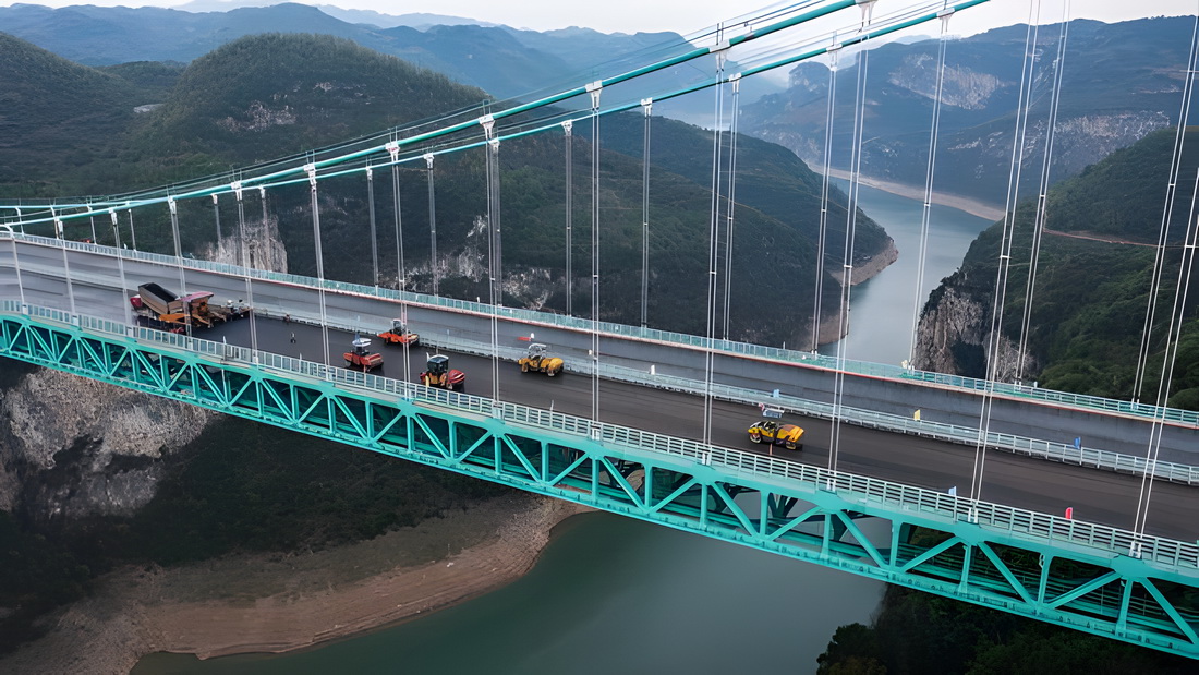 在金烽烏江大橋，貴州公路集團工人駕駛攤鋪機進行橋面鋪裝施工（無人機照片，4月3日攝）。