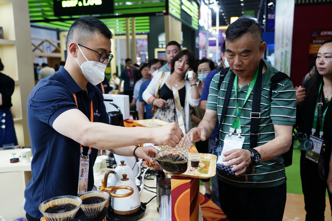 4月12日，參觀者在消博會現場品嘗牙買加藍山咖啡。新華社記者 樊雨晴 攝